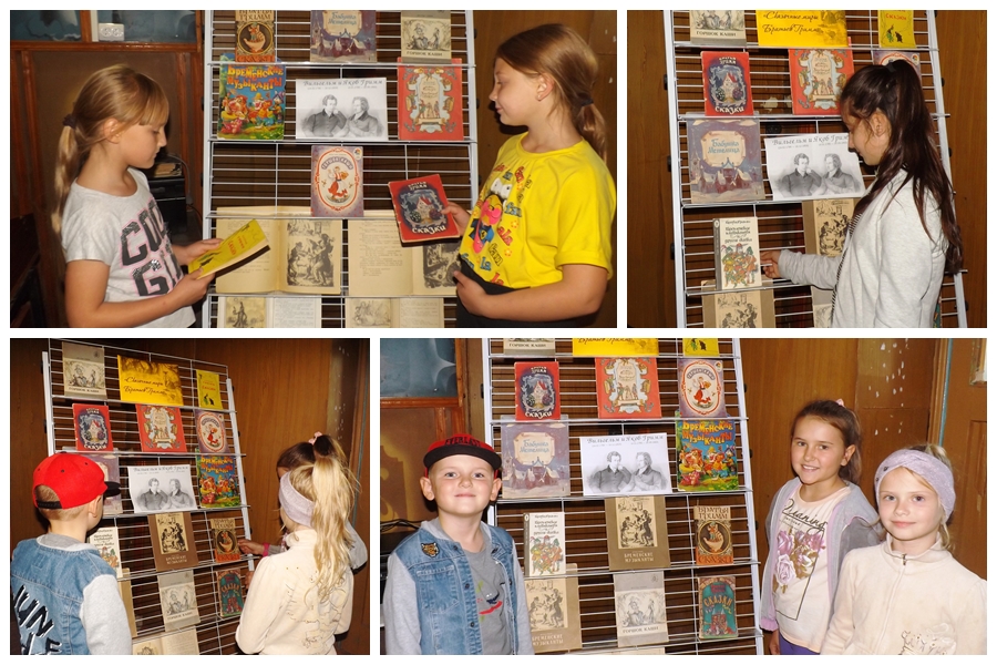 на фото дети рассматривают книги на выставке «Сказочные миры братьев Гримм»